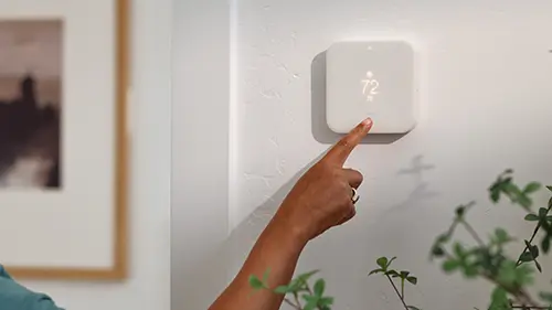 Close Up Of Woman Setting Digital Smart Heating Thermostat At Home