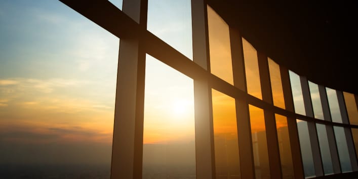 A series of large windows showing sunlight peeking through cloud cover.