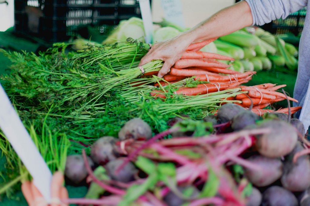 Market stall with fresh carrots beets and corn.